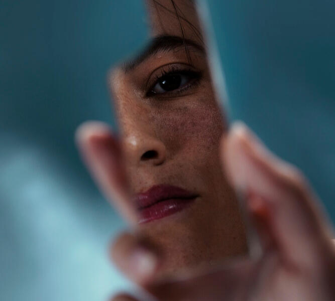 Woman looking in a broken piece of glass